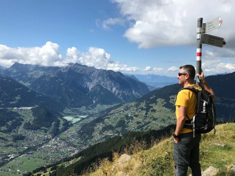 Ein Wanderer blickt vom Gipfel aus zufrieden ins Tal (Montafon, Schruns)
